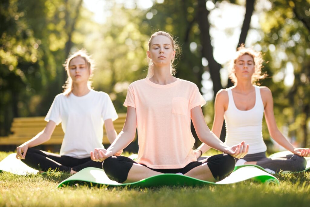 group of young women practicing yoga morning meditation in nature at the park.jpg